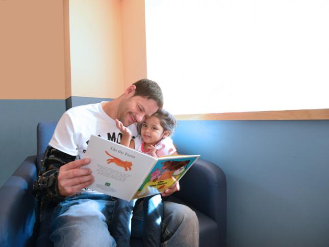 当他读她一本书时，患者Sanayah Pineiro坐在爸爸上